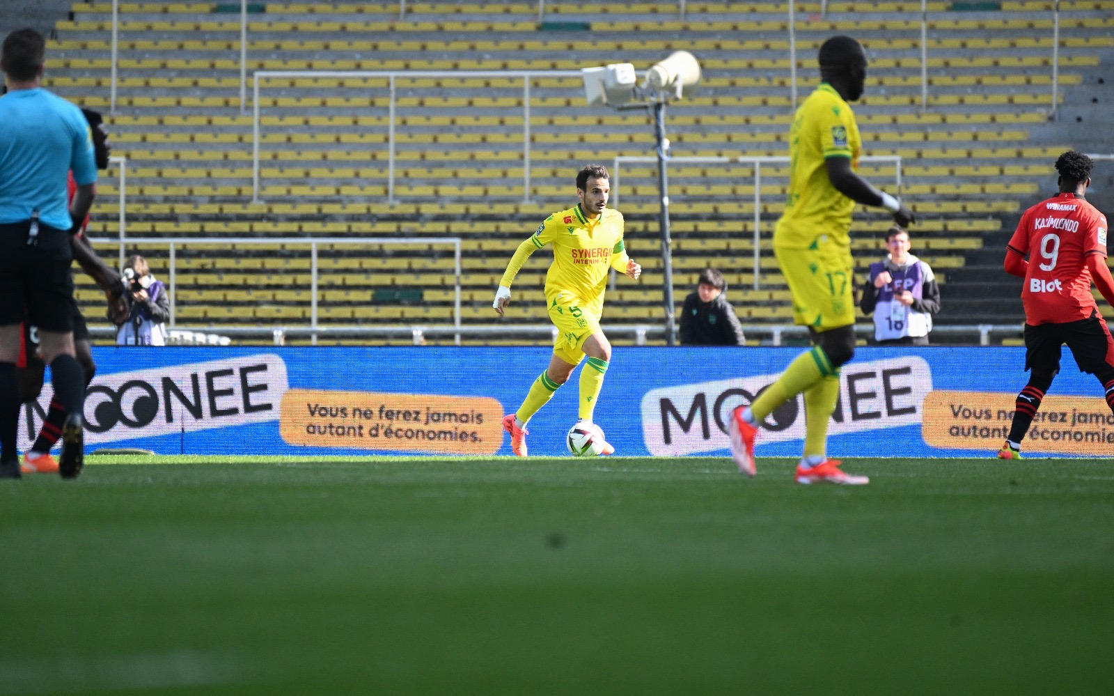 Écran avec la marque Moonee, derrière les joueurs du FC Nantes qui jouent sur le terrain
